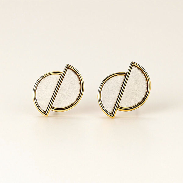 Pair of gold and white earrings on a beige background