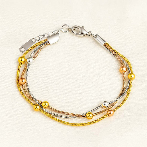 Multistrand bracelet with gold and silver beads on a beige background